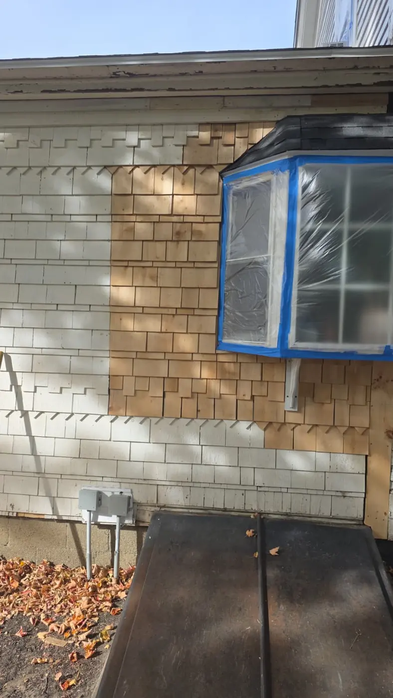 Before: patched shingles around a taped bay window