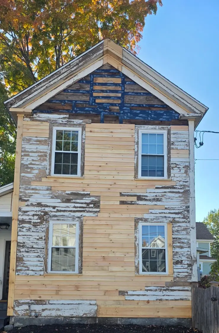 New wood siding boards installed among old weathered clapboards