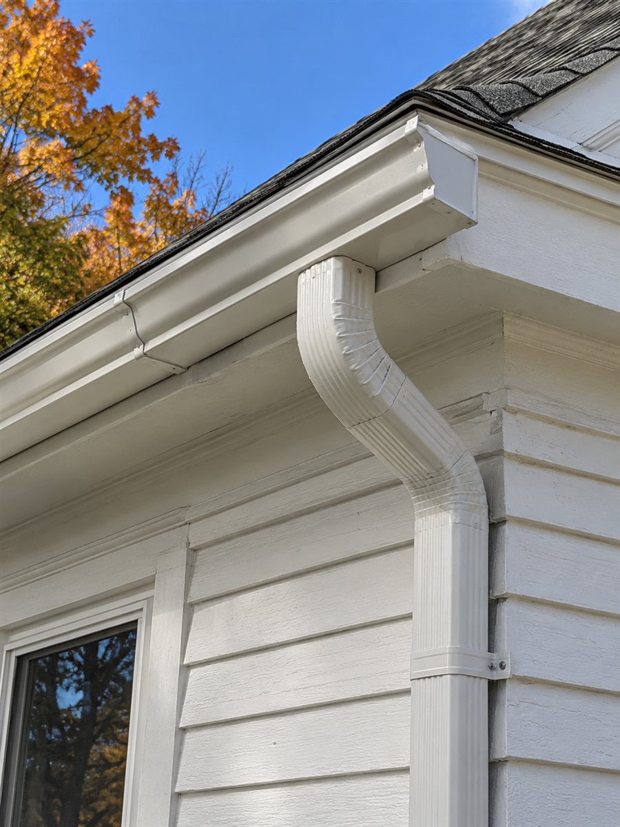 White painted gutter and downspout on a clapboard house